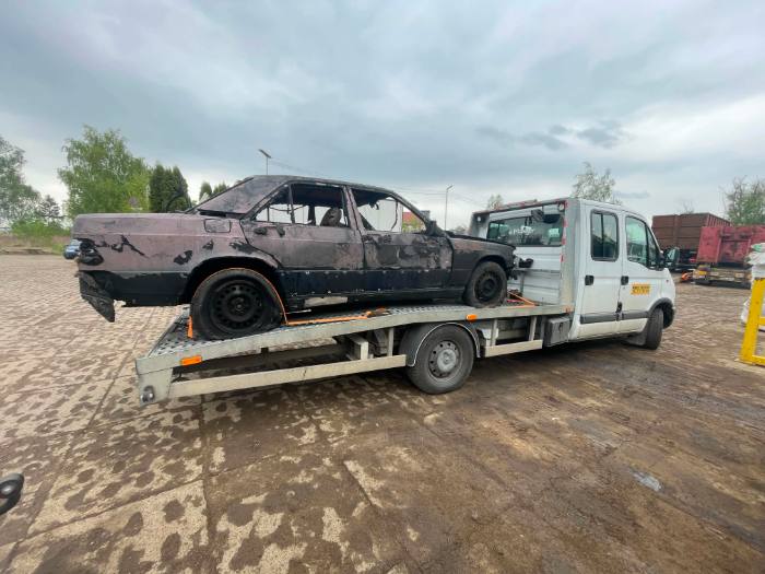 Spalony Mercedes 190 na lawecie — widok z boku